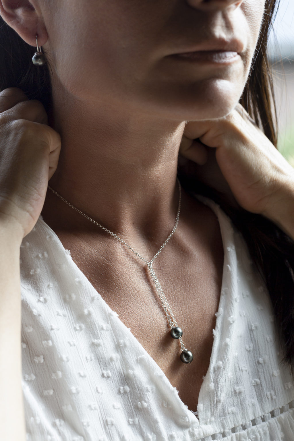 Photo couleur d'un femme portant un pendentif avec deux perles de culture noires