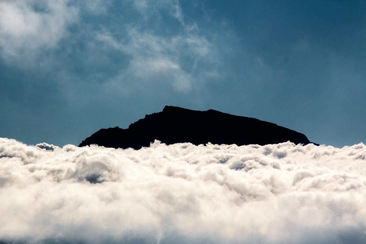 Photographie couleur, format paysage, représentant le sommet du Dolomieu à la Réunion, au dessus d'une mer de nuage.